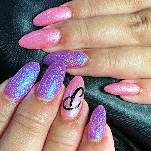Almond acrylic nails in pink and iridescent purple glitter, with a black heart design on one nail.