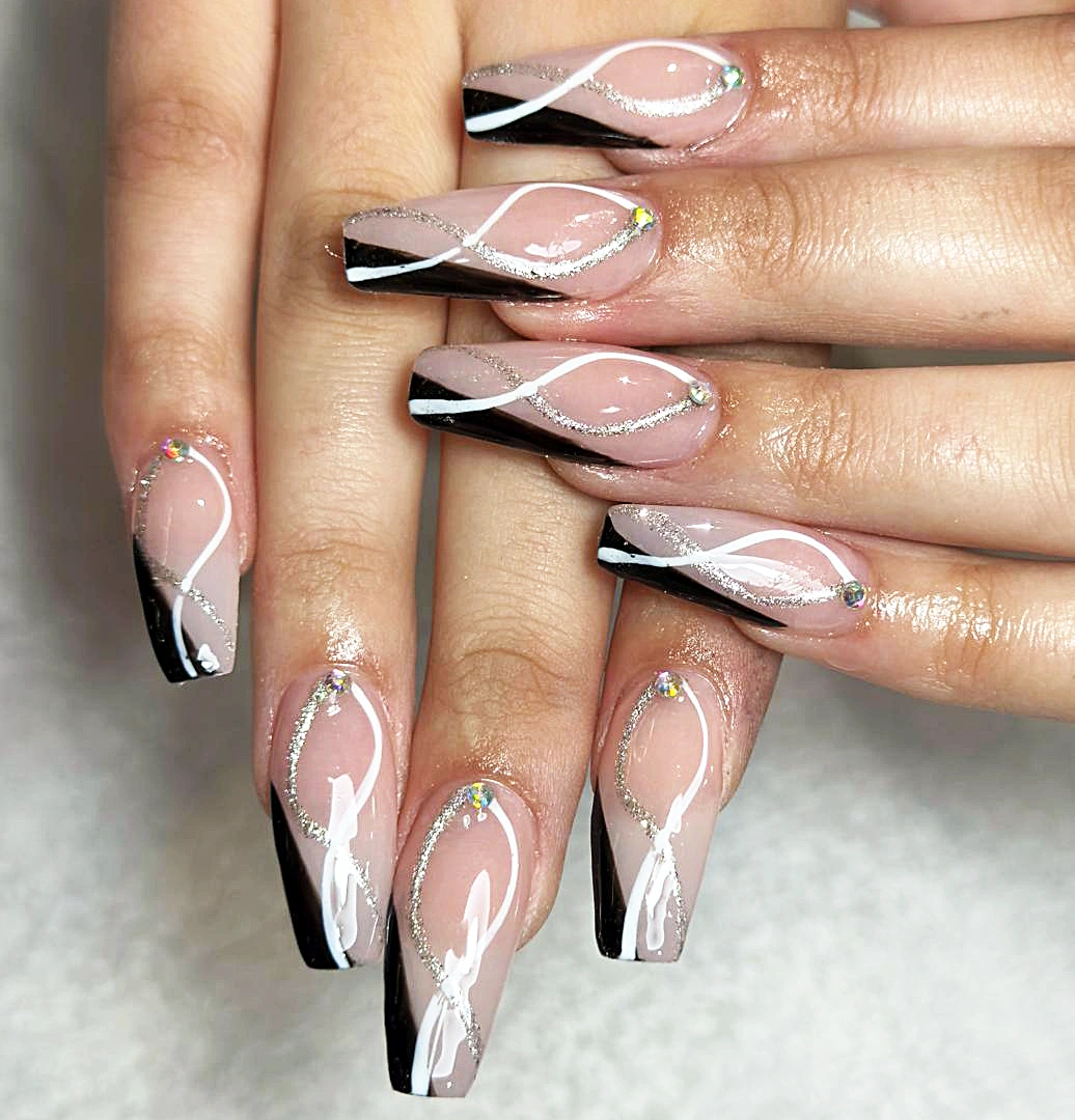 Long coffin nails with a nude base, black tips and white swirl nail art.