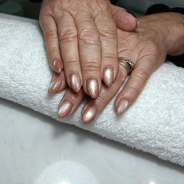 Hands with long, glossy pale pink acrylic nails, two adorned with small rhinestones, and a silver ring with a large gemstone.