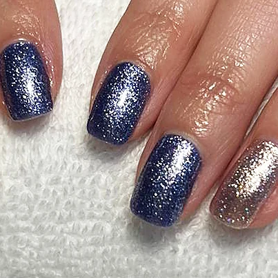 Short natural nails in navy glitter with a rose gold glitter accent nail.
