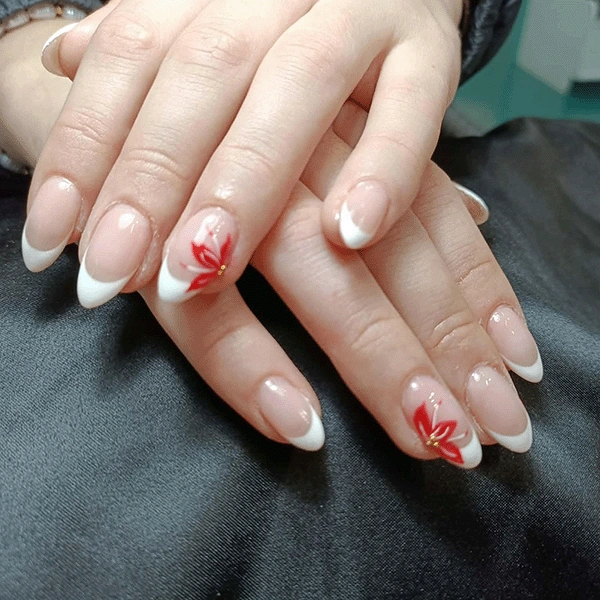 Almond nails with white French tips and a red flower design on two accent nails.