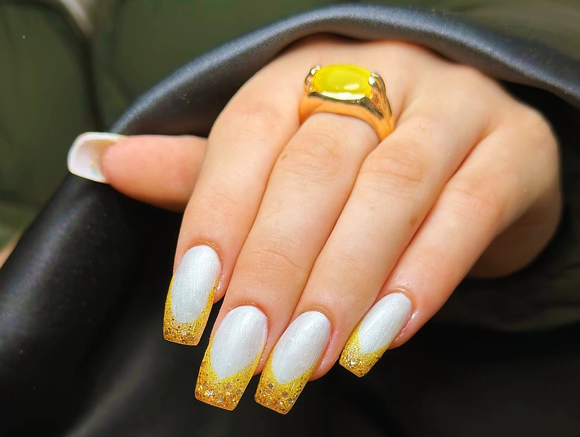 Long square nails with a white base and yellow glitter tips.